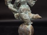 bronze statue of a boy sitting on a ball with a bird in his hand