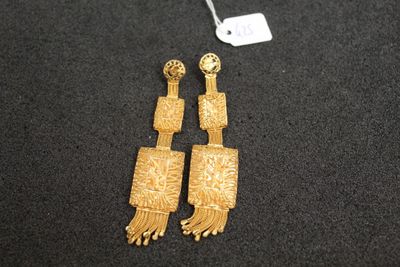 une paire de boucles d'oreilles en or ornées de franges sur un fond noir