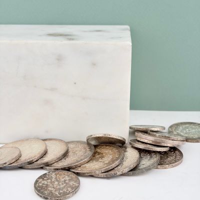 un bloc de marbre blanc posé sur une table, à côté d'une pile de pièces de monnaie