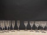 six empty wine glasses lined up on a table against a black background