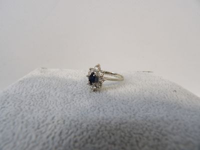 une photo d'une bague sertie d'un diamant et d'un saphir, posée sur un coussin
