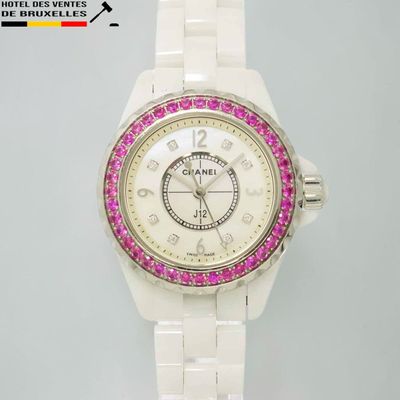 une montre blanche ornée de pierres roses sur la lunette