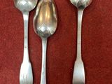 three silver spoons with a note on them sitting on a red surface