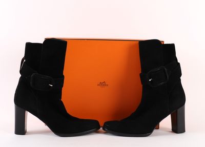 une paire de bottines noires en daim, avec des boucles et une boîte