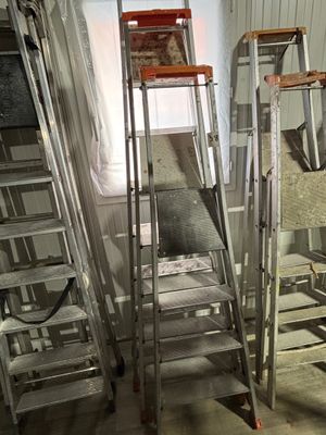 trois échelles dans une pièce, avec une fenêtre en arrière-plan