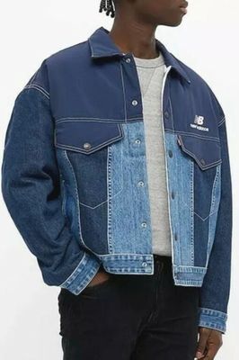 Cet homme porte une veste en jean et un pantalon noir.