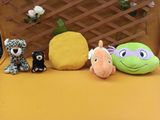 Plusieurs peluches sont alignées en rang sur une surface jaune