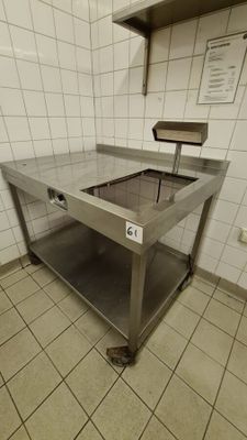 a large stainless steel table in the middle of a tiled room