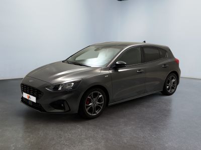 La voiture grise est garée dans une grande pièce au sol noir.