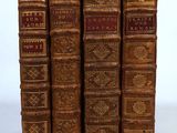 four old books are lined up in a row on a white surface