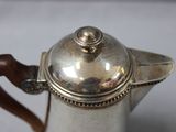 a silver tea pot with a wooden handle on a table