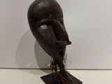 a wooden mask on a stand with a white wall in the background