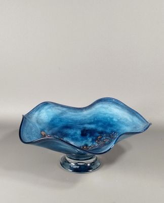un bol en verre bleu posé sur un socle, sur une surface blanche