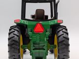 a green toy tractor with large tires on a white surface