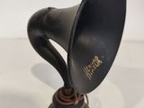 an old fashioned black gramphone on a wooden stand on a white surface