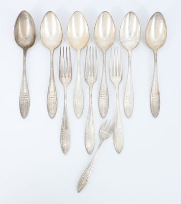 six cuillères et deux cuillères en argent sur une surface blanche