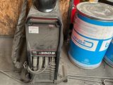 a welder that is sitting on the ground next to some cans