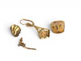 trois bijoux en or posés sur une surface blanche