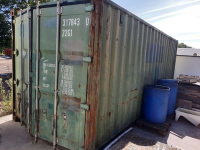 a green shipping container sitting on the side of the road