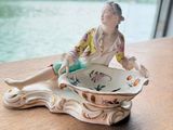 une figurine représentant une femme assise dans un bol posé sur une table