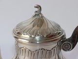 a silver tea pot with a lid on a table