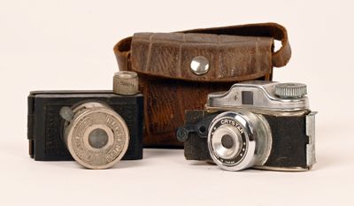 three old cameras sitting next to each other on a white surface