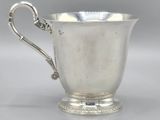 a silver cup with a handle on a stand on a table