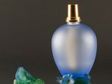two small glass bottles with a gold top and a green flower
