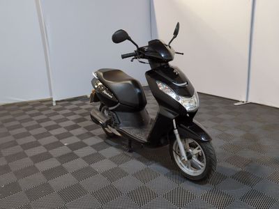 un scooter noir garé dans une pièce au sol en damier