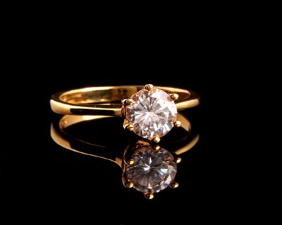 un gros plan d'une bague en or sertie d'un diamant, posée sur une surface noire