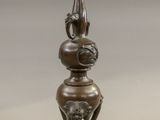 a bronze vase with a bird on top of it
