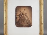 une vieille photo d'une femme en robe, dans un cadre doré