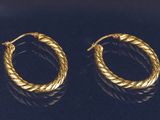 une paire de boucles d'oreilles en or sur une surface noire
