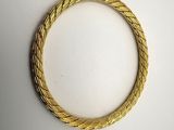 gros plan d'un bracelet en or sur une surface blanche