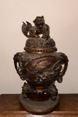 un vase en bronze orné d'un dragon, posé sur une table en bois