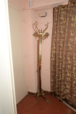un porte-manteau dans un coin d'une pièce où se trouve un rideau