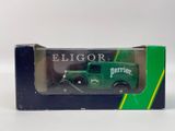 un petit camion vert dans une boîte, posé sur une surface blanche