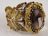 bracelet en or orné d'une grosse pierre entourée de feuilles et de fleurs