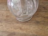 a clear glass vase on a wooden table with a purple wall in the background