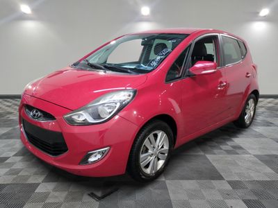 a red car is parked in a room with a checkered floor