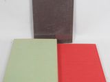 three books sitting next to each other on a white surface