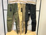 trois pantalons pour homme suspendus à un portant dans un magasin de vêtements