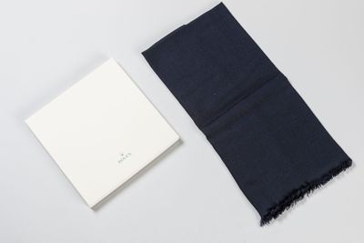 a black scarf next to a white book on a white surface