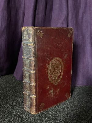 un vieux livre posé sur une table, à côté d'un rideau violet