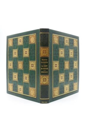 un vieux livre à la couverture verte posé sur une table blanche