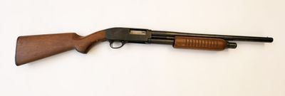 un fusil de chasse posé sur une surface blanche, muni d'une crosse en bois