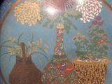 a picture of a decorative plate with a vase and flowers on it