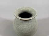 a white vase with a black rim sitting on a white surface