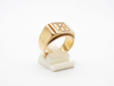 un gros plan d'une bague en or posée sur un bloc de marbre