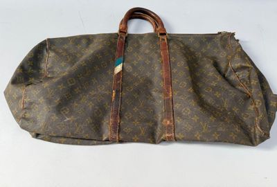 un vieux sac Louis Vuitton avec une poignée marron et des anses marron